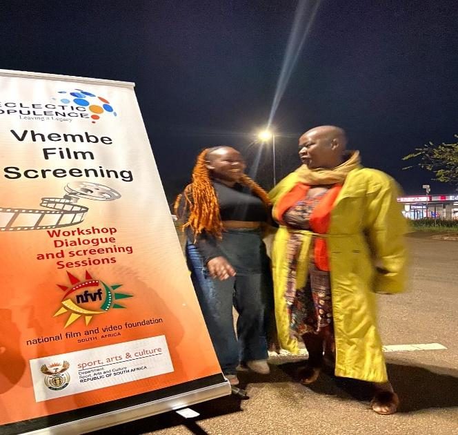 Presenters beside an event banner